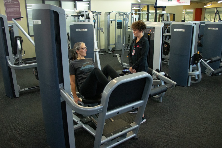 Trainer helping member with an exercise machine