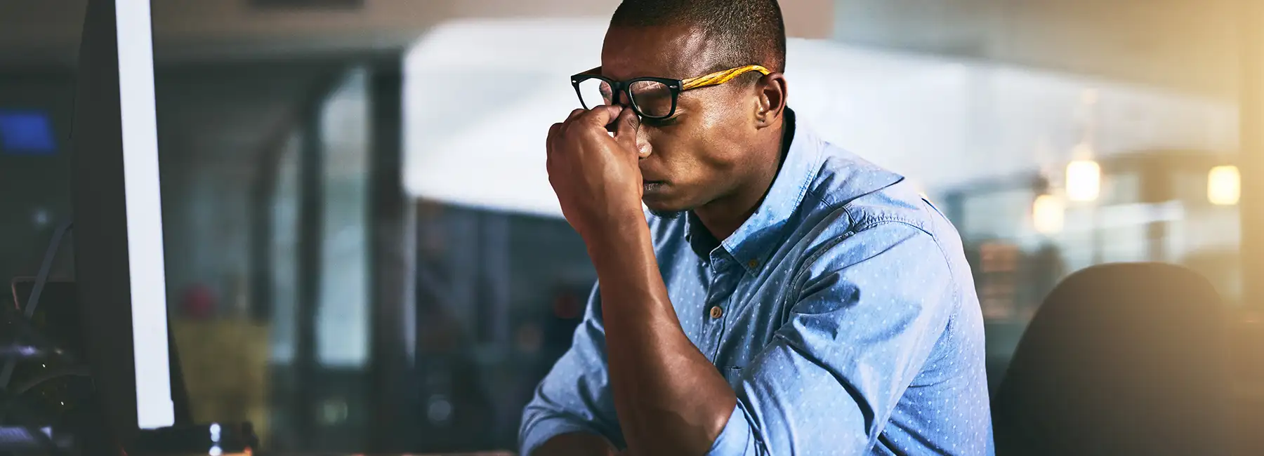 man at desk with headache in visible pain