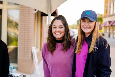 Two young women wearing pink in support of those with breast cancer posing for photo